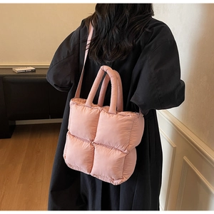 Rear view of a model wearing a pink quilted puffer tote bag with dual straps