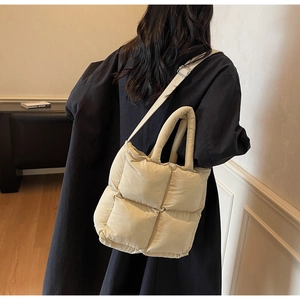 Close-up of quilted down cotton tote bag showing beige checkered patterns and long straps