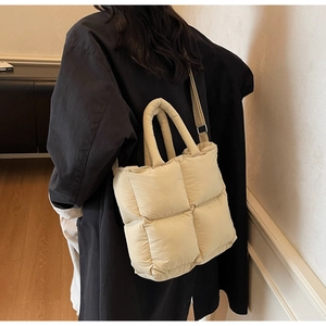 Macro view of cream quilted puffer shoulder bag with soft nylon texture and wide handle