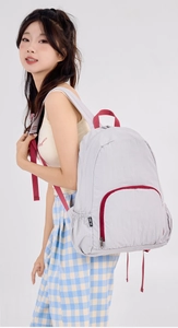 Light gray foldable nylon backpack featuring red zipper trim and side storage pocket