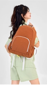 Brown lightweight foldable nylon backpack with white piping zip pocket and adjustable straps