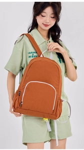 Detail of a lightweight terracotta foldable backpack with white piping on the front pocket