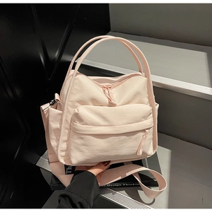 Makro-Detail einer hellrosa Nylontasche mit Doppelgriffen und praktischer Seitentasche
