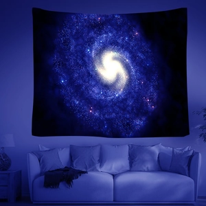 Close-up of starry galaxy tapestry with deep blue swirls hung above a sofa for room decor