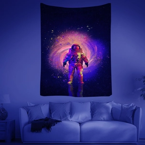 Detalle de tapiz fluorescente de neón con astronauta y nebulosa colgado en la pared