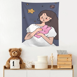 Detail of cartoon girl and bunny tapestry hanging on a white wall in a cozy room