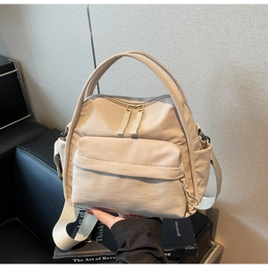 Details der beigefarbenen Nylontasche mit Frontklappentasche und Doppeltragegriffen