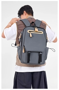 Close-up of grey ergonomic backpack showing multi-zipper pockets and brown leather pullers