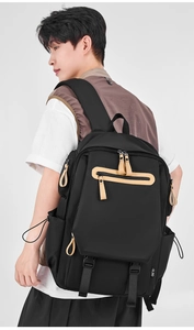 Detailed side view of black canvas backpack with khaki leather pullers and buckle straps