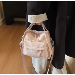Detail der hellrosa Nylontasche mit breitem Schultergurt und vorderer Reißverschlusstasche
