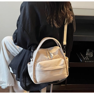 Detail der cremeweißen Nylon-Umhängetasche mit mehreren Taschen und verstellbarem Gurt