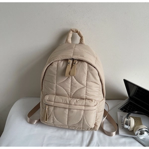 Dettaglio di zaino trapuntato beige con manico imbottito e tasche a cerniera multiple