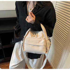 Tragebeispiel der cremefarbenen Nylon-Schultertasche mit praktischen Außentaschen