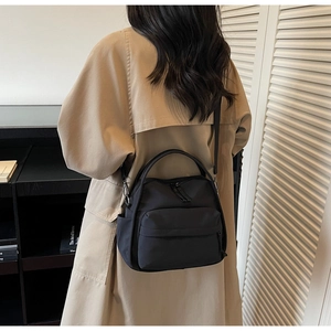 Rückansicht einer schwarzen Nylon-Umhängetasche mit vielen Taschen, getragen von einem Modell