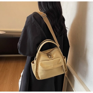 Detailansicht der beigen Nylontasche mit Frontreißverschluss und Seitentasche