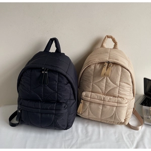 Zaini trapuntati in nero e beige che mostrano i dettagli delle cuciture e le tasche