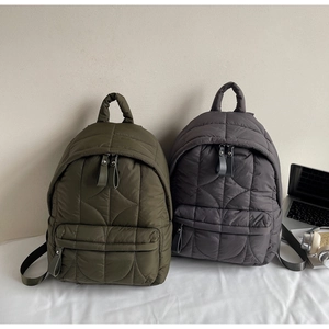 Dettaglio di zaini in nylon trapuntato oliva e grigio con cuciture ondulate e tasche