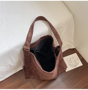 Vista macro della borsa tote in pelle scamosciata marrone scuro con cinturino largo e fibbia