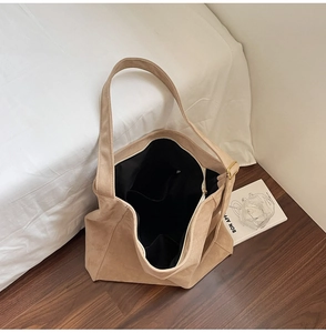 Vista dettagliata della grande borsa tote marrone chiaro con trama scamosciata e tasche