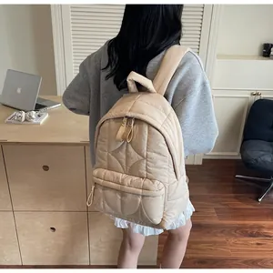 Zaino trapuntato beige con cuciture a onde mostrato in un ambiente da ufficio moderno