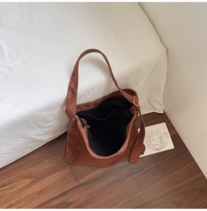 Dettaglio della borsa tote in finto scamosciato marrone con tasca interna e fibbia d'oro