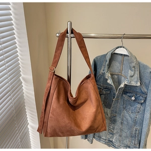 Dettaglio borsa tote in pelle scamosciata marrone con fibbia dorata regolabile