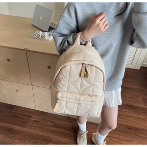 Dettaglio dello zaino trapuntato beige in nylon con motivi a onde e tasca frontale