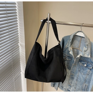 Dettaglio borsa hobo in camoscio nero con ampia tracolla e fibbia dorata regolabile