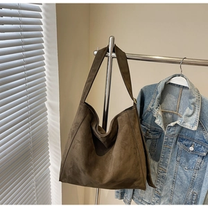 Vista dettagliata della trama in camoscio marrone scuro su una borsa tote minimalista