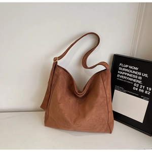 Dettaglio di borsa tote in pelle scamosciata marrone con tracolla larga e fibbia d'oro