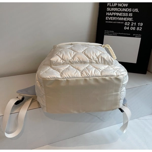 Close-up of the quilted pearl white backpack showing base texture and strap detail
