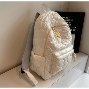 Detail of quilted backpack showing plush cloud texture and woven zipper puller