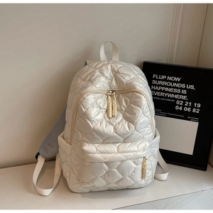 Detailed view of cream quilted puffer backpack with soft padded straps and shiny nylon finish