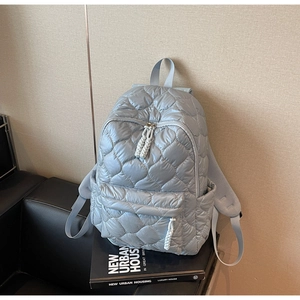 Close-up of quilted wave pattern on light gray puffer backpack with zipper detail