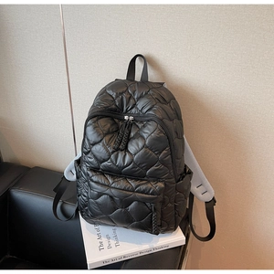 Detail of black quilted backpack featuring diamond texture and grey mesh shoulder straps