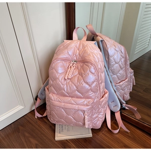 Detail of pink quilted nylon backpack featuring heart pattern and multiple pockets