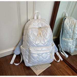 Detail of white quilted puffer backpack featuring side pockets and breathable mesh straps