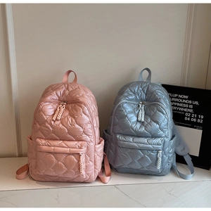 Close-up of quilted nylon backpacks in pink and blue with braided rope zipper pulls