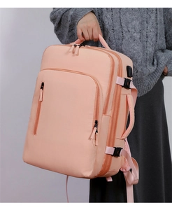 Pink travel backpack detail featuring external USB charging port and side buckle straps