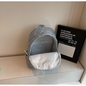 Detail of the light blue quilted backpack interior featuring white lining and inner compartment