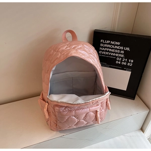Detail view of pink quilted backpack with heart pattern and open interior storage