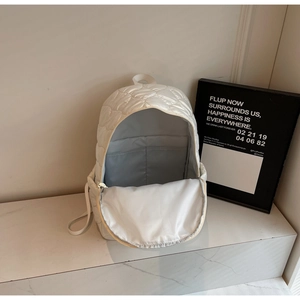 Detail of quilted nylon backpack featuring zipper opening and grey inner lining