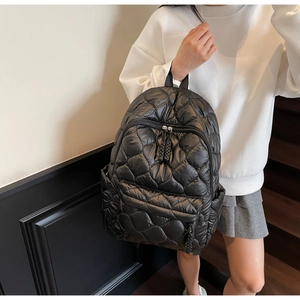 Detail of black quilted puffer backpack featuring classic diamond stitching and front pocket