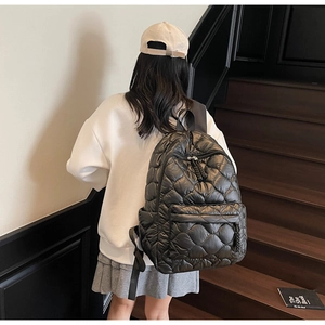 Rear view of a black quilted puffer backpack styled with a casual outfit on stairs