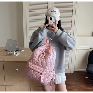 Lifestyle view of a pink quilted puffer backpack with soft cloud-like texture and front pocket