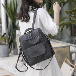 Detail of vintage grey PU leather backpack showing versatile straps and multi-pocket design