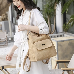 Outdoor shot of a khaki PU leather backpack with a magnetic flap pocket and metal logo