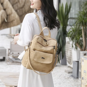 Khaki PU leather backpack shown on a model in an outdoor setting with adjustable straps