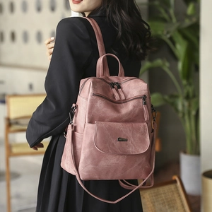 Detail of pink vintage PU leather backpack featuring metal bar buckle and multiple zip pockets