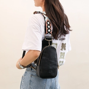 Detail of black pebbled PU leather chest bag with a colorful bohemian woven strap